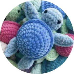 Many crochet turtles in a pile with a blue crochet turtle on top
