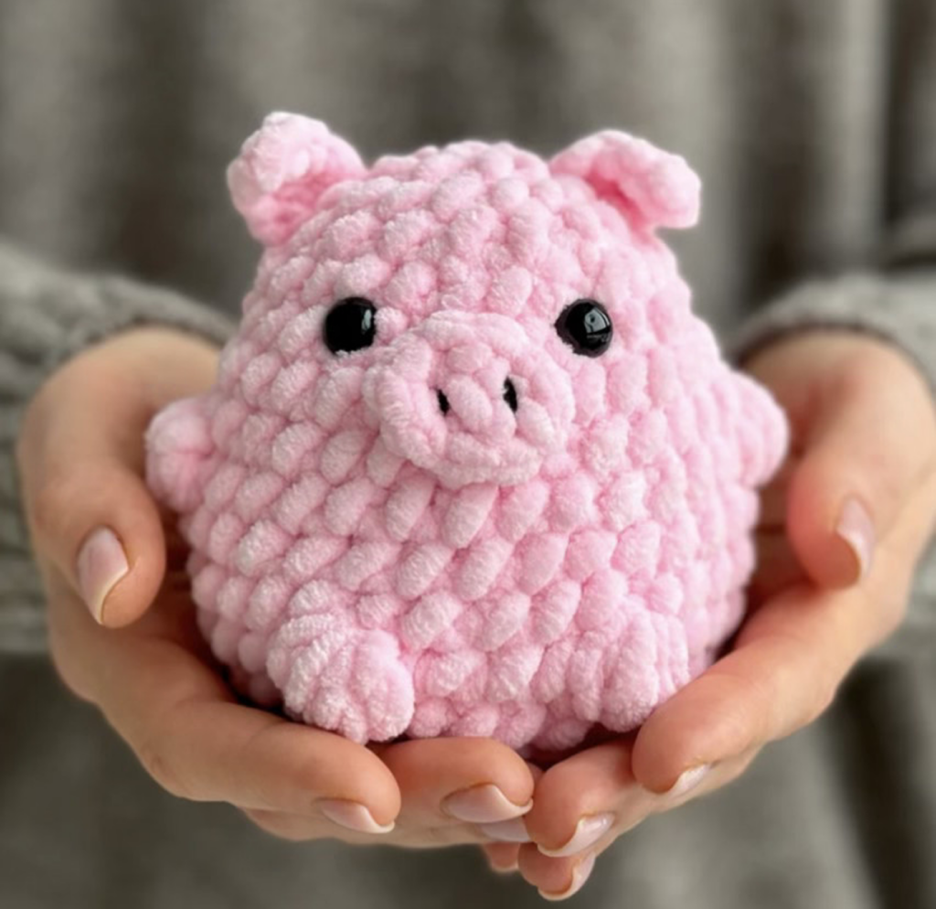 Woman holding a crochet pink pig